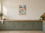 The Fishermans Lunch — A2 artwork shown in a room with a natural wood frame; select a framed finish to include a frame