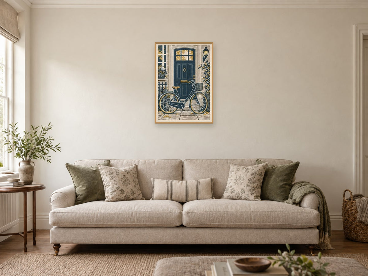 The Bicycle by the Door — A2 artwork shown in a room with a natural wood frame; select a framed finish to include a frame